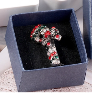 Close-up of Christmas candy cane brooch with red and green rhinestones in a blue gift box