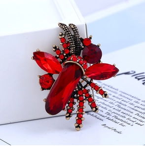 Detailed macro view of vintage insect brooch with red gemstones and bronze metal base