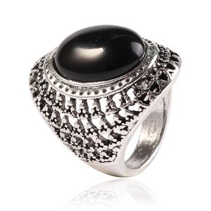 Macro detail of vintage silver ring featuring a large oval black stone with filigree patterns