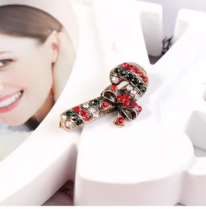 Macro detail of Christmas candy cane brooch with red green crystals on gold alloy