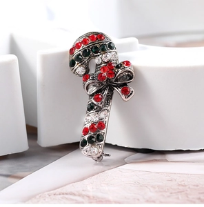 Macro shot of silver alloy Christmas candy cane brooch with red and green rhinestones