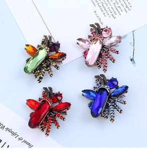Macro detail of four insect brooches with colorful gemstones and vintage bronze base