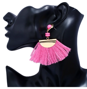 Detail of rose pink tassel earrings on a black mannequin featuring golden metal disc