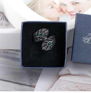 Detalle de anillo de pluma vintage con piedras esmeralda en gota en una caja de regalo azul