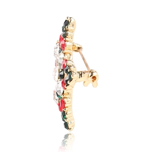 Golden Christmas star brooch with red green crystal stones side view in a white background