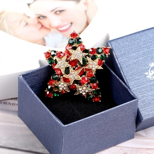Vue détaillée d'une broche étoile de Noël avec strass colorés dans son coffret cadeau