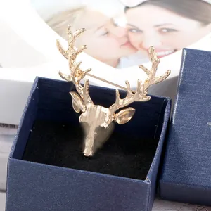 Close-up of golden hollow deer head brooch inside a luxury navy blue jewelry gift box