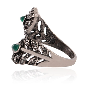 Detalle del anillo de pluma vintage con gemas verdes y acentos de mosaico negro
