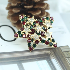 Broche étoile de Noël avec strass rouges verts et accents dorés sur fond de pomme de pin