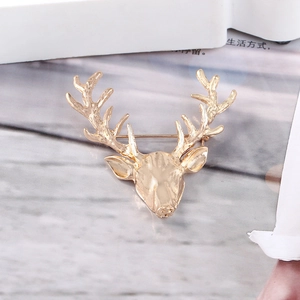 Close-up of a gold hollow deer head brooch with glossy finish on a lifestyle background