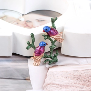 Detailed close-up of colorful cloisonné enamel bird brooch resting on a green twig