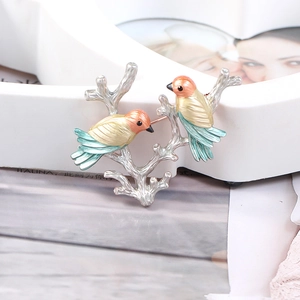 Detailed view of colorful enamel bird brooch on a silver twig with magpie design
