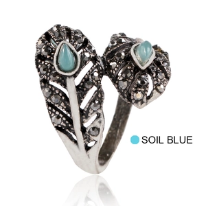 Detalle de anillo de pluma plateado con piedras negras y acentos de cristal azul