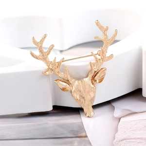 Macro detail of golden hollow deer brooch with safe pin on white geometric heart