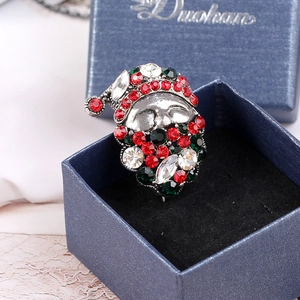 Detailed macro view of a Santa Claus brooch with red and green rhinestones in a gift box