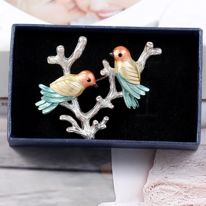 Detail of vibrant enamel double bird brooch on a silver branch in a gift box
