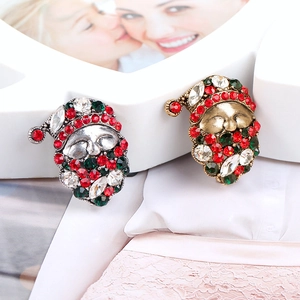 Close-up of gold and silver Santa Claus brooches with colorful rhinestones on white lace