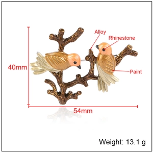 Creative enamel bird brooch with rhinestones and orange feathers on a branch