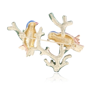 Enameled bird brooch on golden branches featuring secure safety pin and brushed metal back