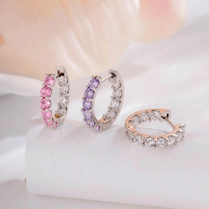 Elegant silver hoop earrings set with colorful zircon stones on a white podium