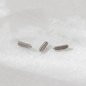 Drei silberne F136 Titan Gewindestifte für Körperschmuck Ersatzteile auf weißer Baumwolle