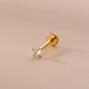Dettaglio di un piercing in acciaio dorato con zircone rotondo e base piatta liscia