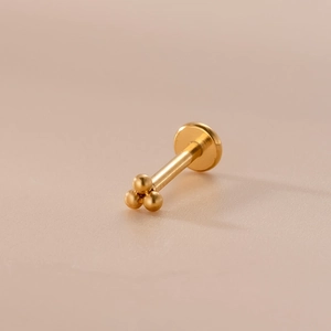 Dettaglio del piercing labret 16G dorato con sommità a tre sfere e base piatta