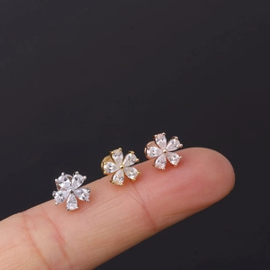 Macro view of three-color zircon flower labret studs held against a finger for scale