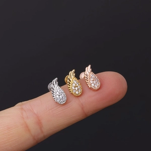 Macro shot of 16G stainless steel labret studs with micro-set zircon feathers on fingertips