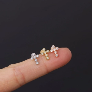 Macro view of 16G stainless steel cross ear studs with cubic zirconia on fingertips