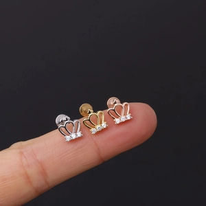 Three-color crown ear studs with micro-set zircons shown on a fingertip for scale