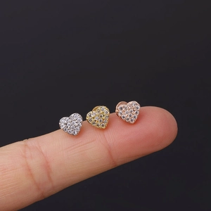 Macro detail of heart-shaped micro-pave ear studs in gold, silver and rose gold