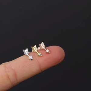 Close-up of 16G stainless steel arrow labret studs in silver, gold, and rose gold finishes