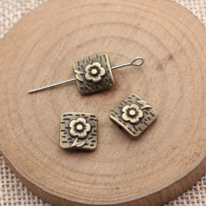 Antique bronze flower square spacer beads for DIY jewelry making on wooden background