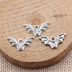 Three antique silver bat pendants for jewelry making on a wooden display block