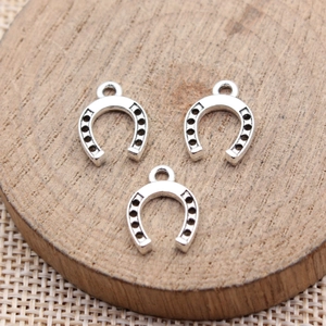 Three horseshoe alloy charms with silver finish on wood, DIY jewelry making accessory