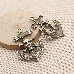 Set of two vintage bronze skull and anchor charms with rustic metallic texture and carvings