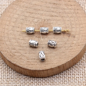 Antique silver triangle pattern spacer beads displayed on natural wood texture background