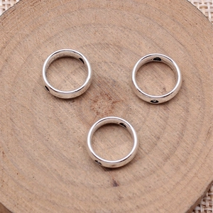 Three minimalist silver steel rings with black dot accents on a rustic wood background
