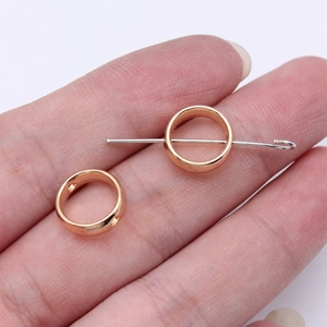 Rose gold circular spacer beads for jewelry making shown with a pin for size reference