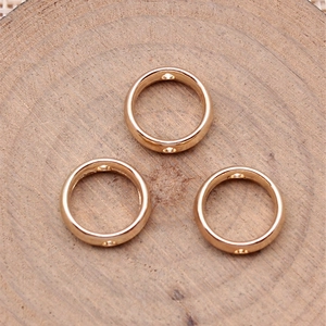 Three gold-plated circular beads for jewelry DIY, set on a natural wooden background