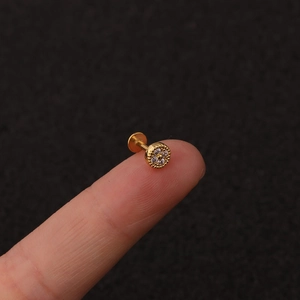 Macro view of gold flower labret stud with cubic zirconia inlays on a fingertip