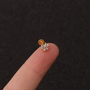 Macro shot of 3-stone zircon flower lip stud in gold stainless steel on a fingertip