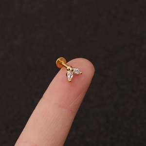 Macro view of gold flower cartilage stud with marquise cubic zirconia on a fingertip