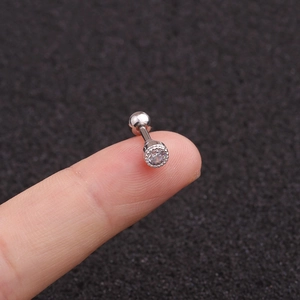 Dettaglio macro di un piccolo orecchino in acciaio inossidabile con zircone rotondo