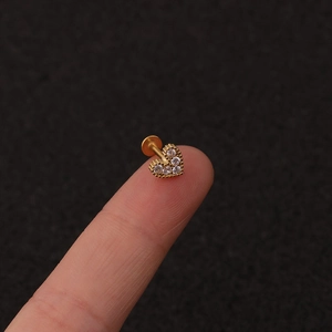 Macro shot of gold heart labret stud with inlaid zircons held on a fingertip for size