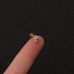 Macro view of gold flower piercing with cubic zirconia held on a fingertip for size