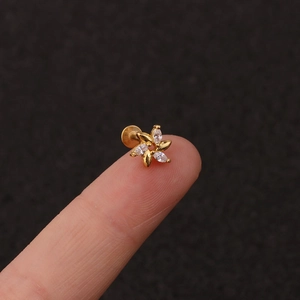 Macro view of gold flower cartilage piercing with marquise cut zircon petals in hand
