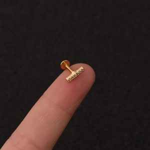 Macro shot of gold stainless steel stud with zirconia inlay on a fingertip