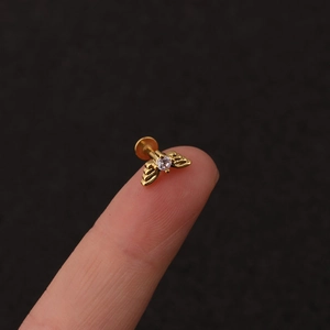 Detailed view of a small golden bee labret stud with zircon on a fingertip